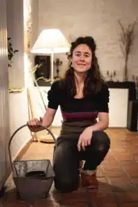 Femme tenant un seau devant un lampadaire allumé, posant en souriant.